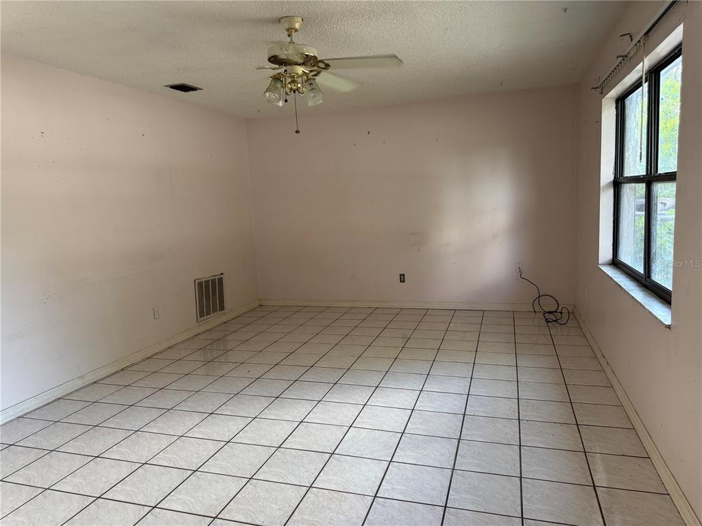 An empty room with light pink walls, white tiled floors, and a ceiling fan — 2479 KIMBERLY DRIVE, DELTONA, FL