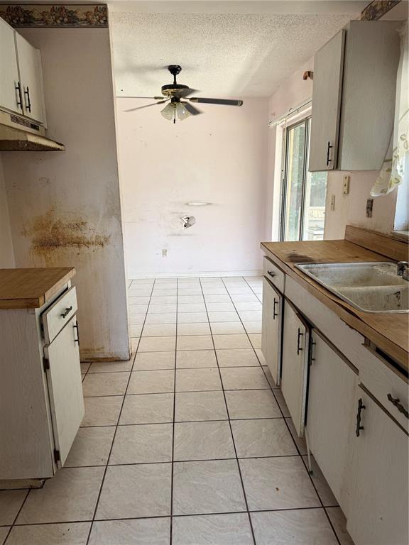 A kitchen with white cabinets, wood countertops, tiled floors, and a ceiling fan — 2479 KIMBERLY DRIVE, DELTONA, FL