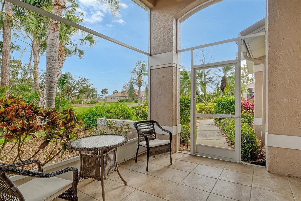 A screened-in patio features tile flooring, wicker furniture, and a view of the outdoors — 9411 FOREST HILLS CIRCLE, SARASOTA, FL