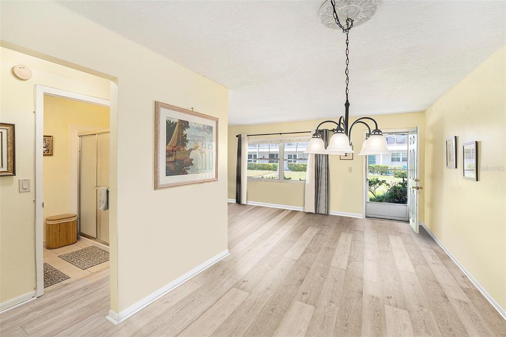 A dining area with light wood-look flooring, a chandelier, and an open doorway to a bathroom — 5216 81ST STREET N UNIT 2, ST PETERSBURG, FL