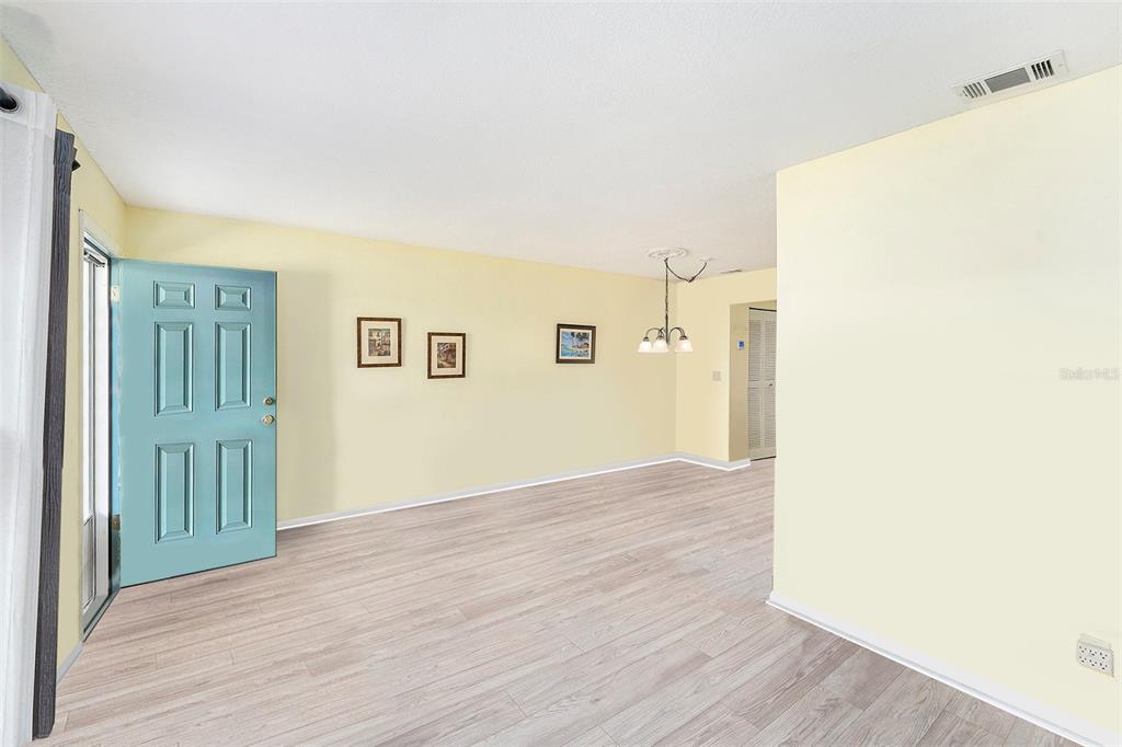 An empty room with light yellow walls, light wood-look flooring, and a blue front door — 5216 81ST STREET N UNIT 2, ST PETERSBURG, FL