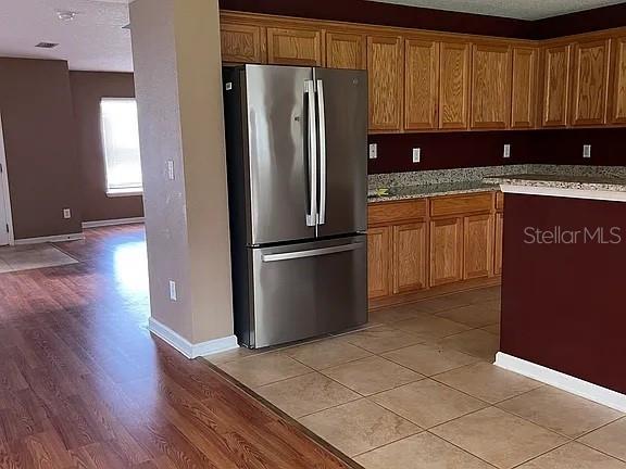 A kitchen features oak cabinets, stainless steel appliances, and tile flooring adjacent to wood flooring — 70 ROLLINS LANE, PALM COAST, FL