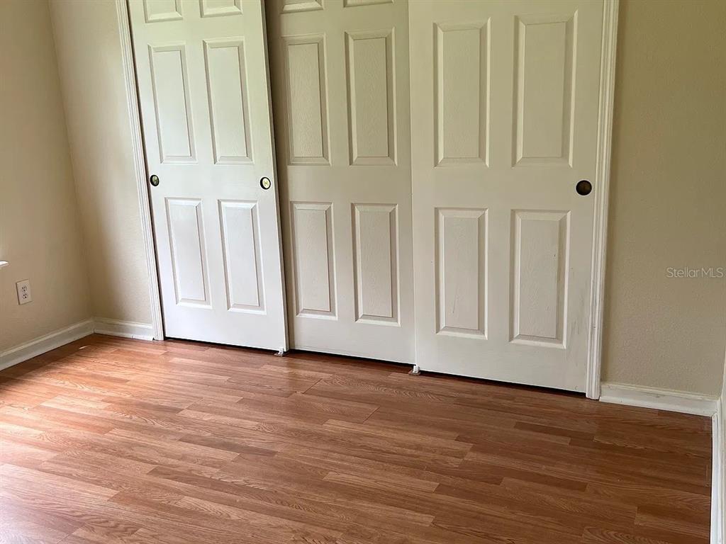A room with light-colored walls, wood-look flooring, and a set of white sliding closet doors — 70 ROLLINS LANE, PALM COAST, FL