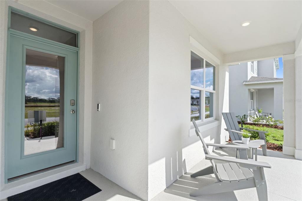 A covered front porch features a light blue door, two gray chairs, and white walls — 5201 MARSHELDER ST, APOPKA, FL