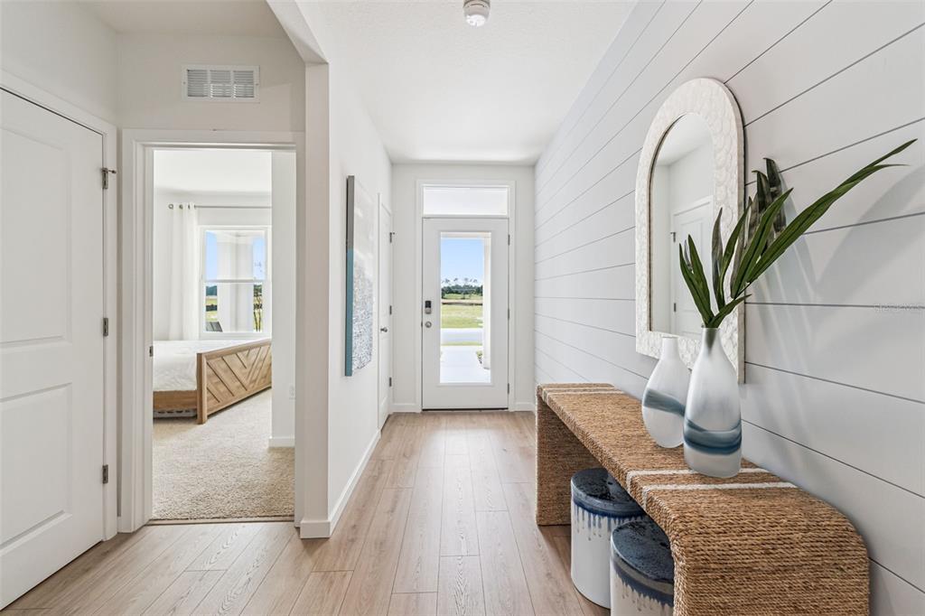 A hallway features light wood flooring, shiplap walls, a console table, and a view of a bedroom — 5201 MARSHELDER ST, APOPKA, FL