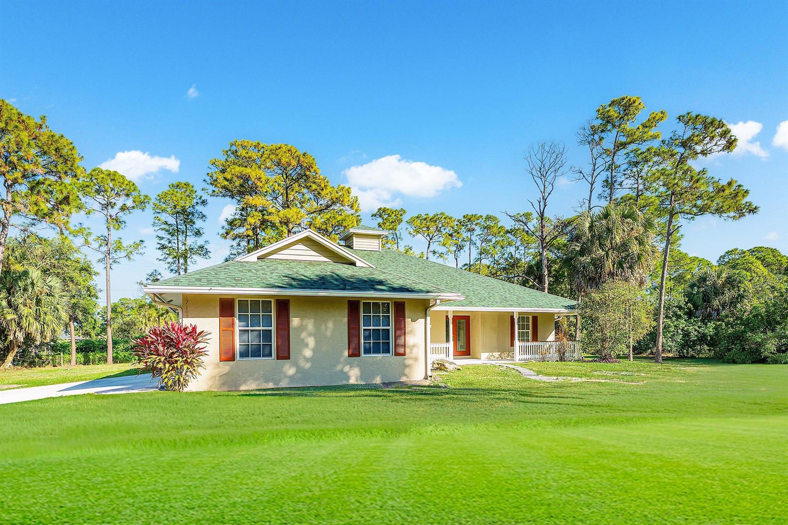 A single-story house with a green roof, tan stucco walls, and red shutters — 17109 Murcott Boulevard, FL 33470, FL
