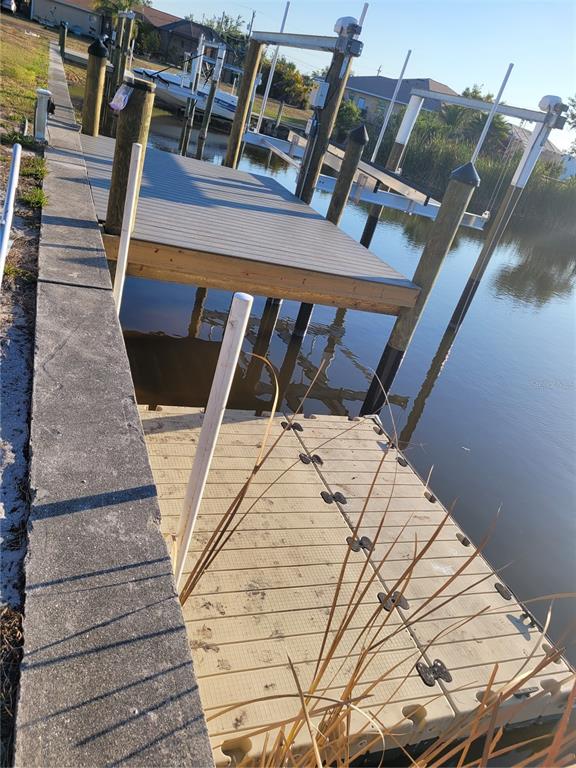 A floating dock sits in the water next to a fixed wooden dock and seawall — 9458 MODESTO CIRCLE, PORT CHARLOTTE, FL