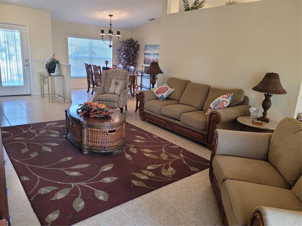 A living room with a brown sofa, patterned rug, and an adjacent dining area — 9458 MODESTO CIRCLE, PORT CHARLOTTE, FL