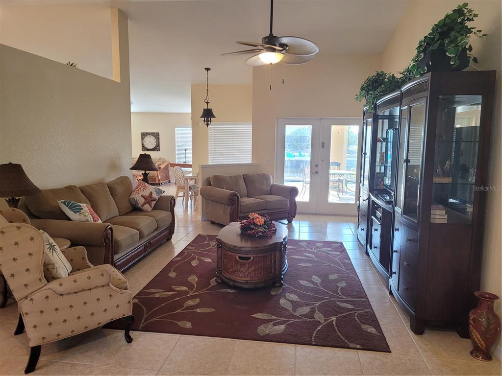 A living room features tile floors, a ceiling fan, a rug, and a large cabinet — 9458 MODESTO CIRCLE, PORT CHARLOTTE, FL