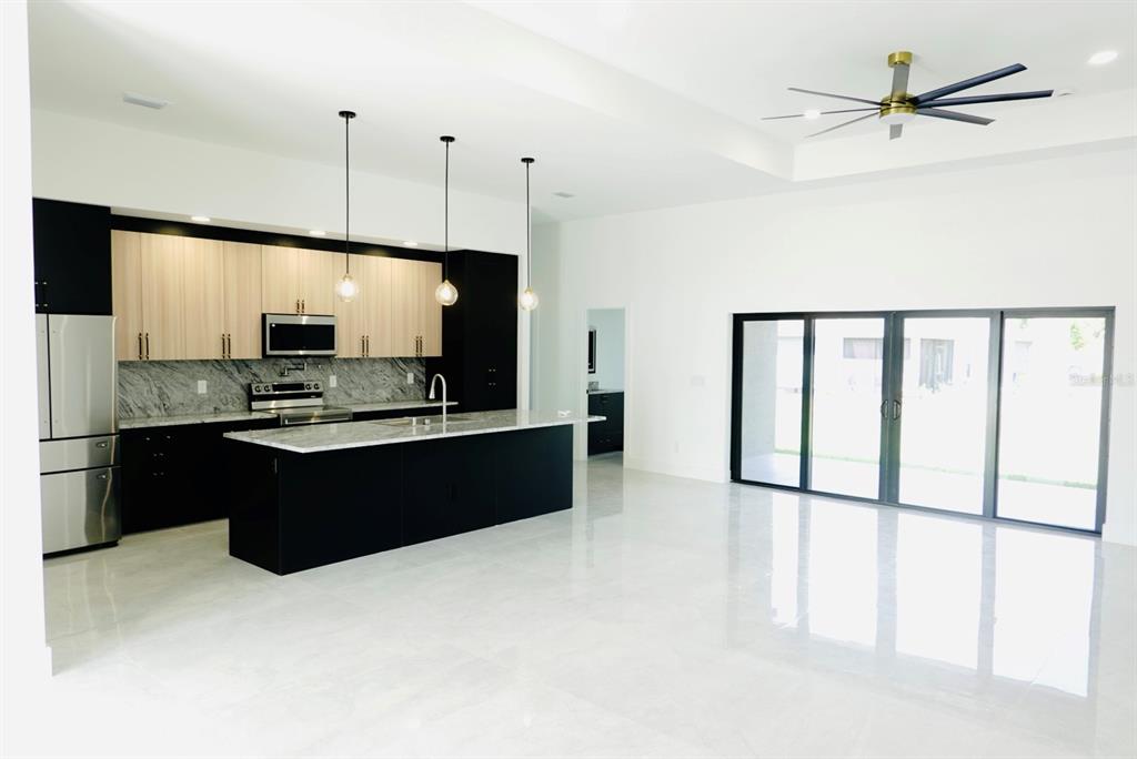 A modern kitchen with black cabinets, light wood uppers, and a large island — 700 BISCAYNE DRIVE, PORT CHARLOTTE, FL