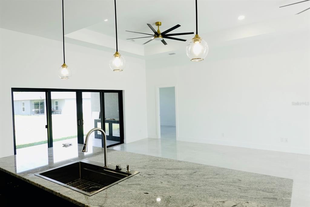 A kitchen island with a sink overlooks a bright living area with a ceiling fan — 700 BISCAYNE DRIVE, PORT CHARLOTTE, FL