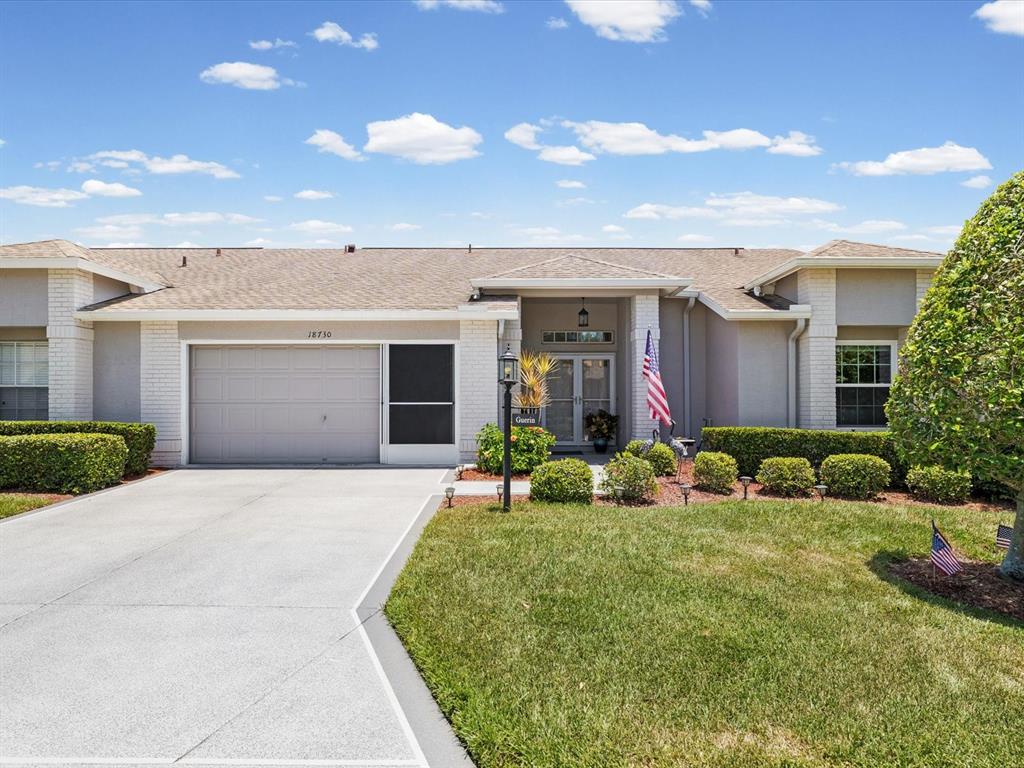 A single-story house with a beige exterior, a two-car garage, and a landscaped front yard — 18730 WORTHINGTON DRIVE, HUDSON, FL