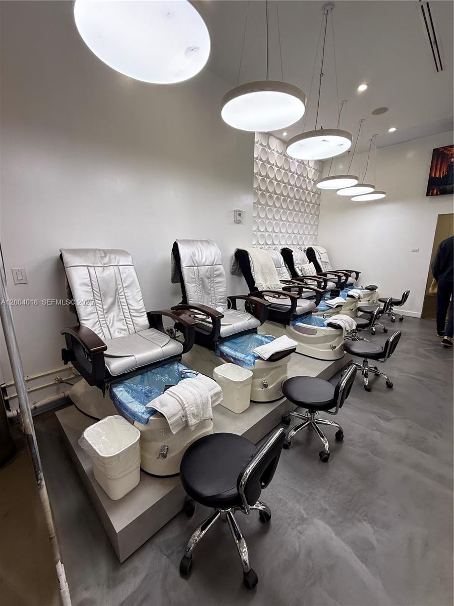 A salon room features a row of pedicure chairs with silver upholstery on a raised platform — Beauty Salon & Spa in Brickell, Miami FL 33131, MIAMI, FL