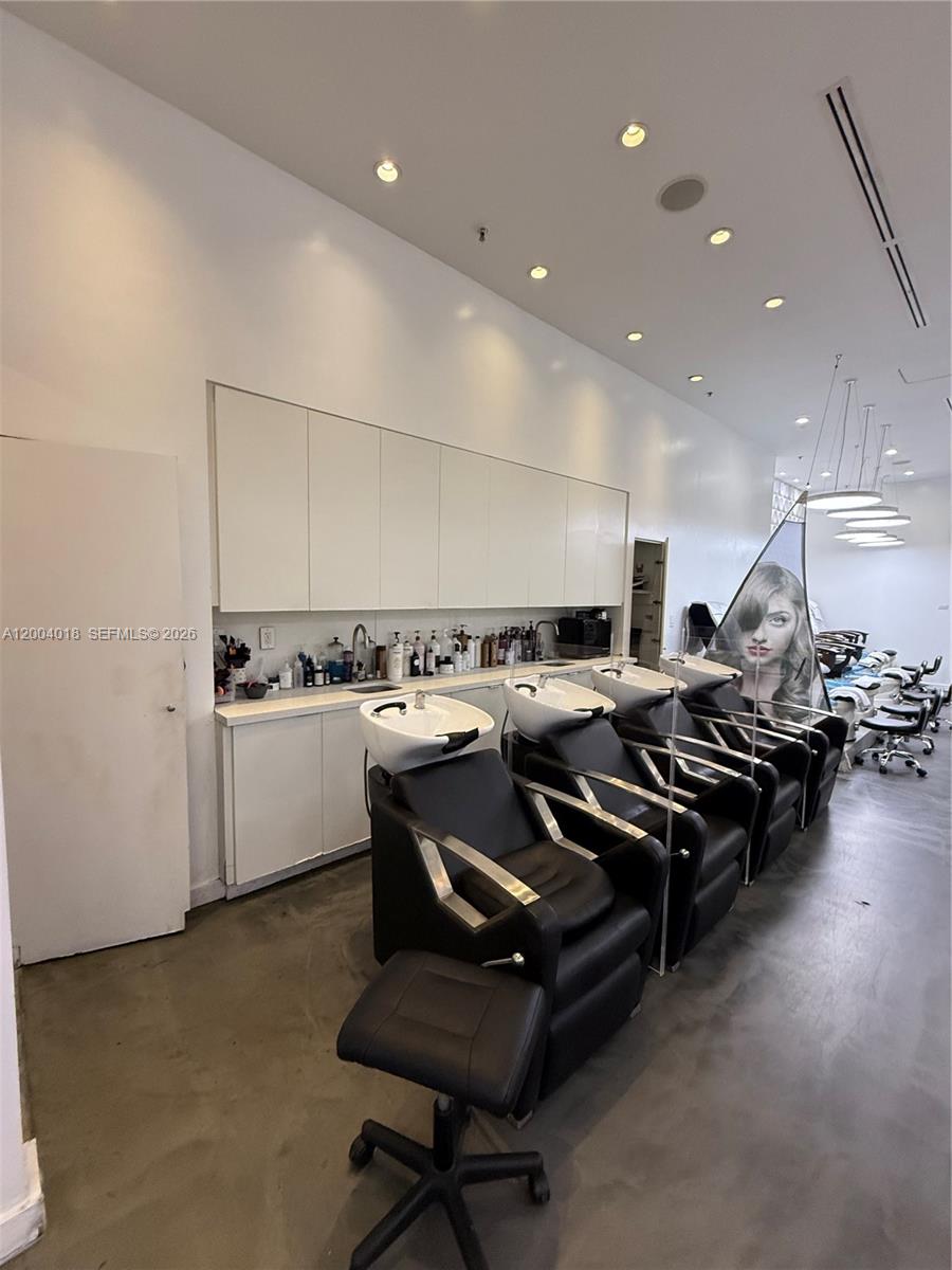 A hair salon features a row of black shampoo chairs with sinks and white cabinetry — Beauty Salon & Spa in Brickell, Miami FL 33131, MIAMI, FL