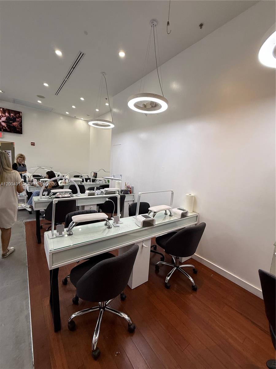 A nail salon features multiple manicure stations with white desks, black chairs, and pendant lighting — Beauty Salon & Spa in Brickell, Miami FL 33131, MIAMI, FL