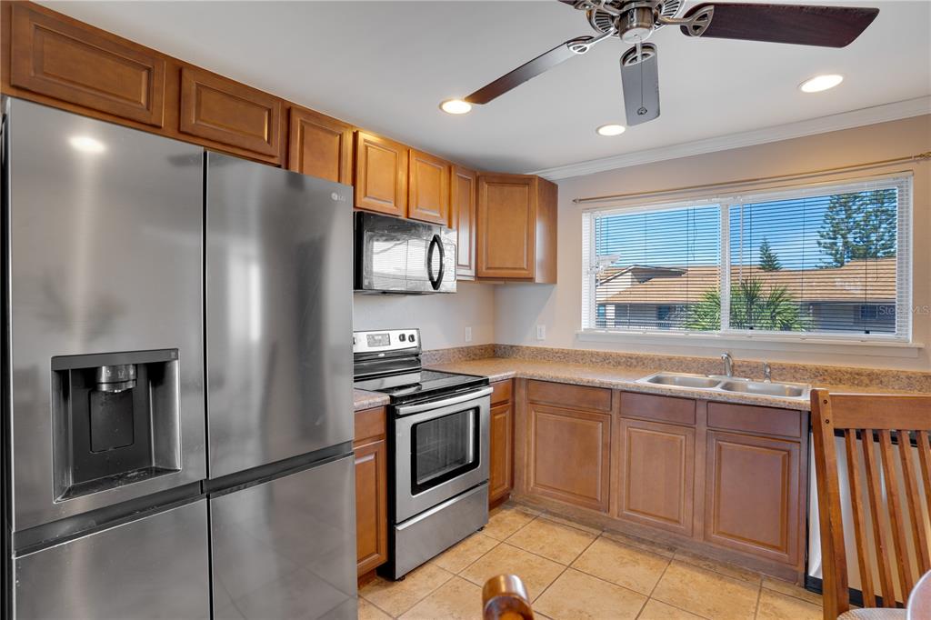A kitchen with stainless steel appliances, wood cabinets, tile flooring, and a window over the sink — 6315 NEWTOWN CIRCLE UNIT 15B3, TAMPA, FL