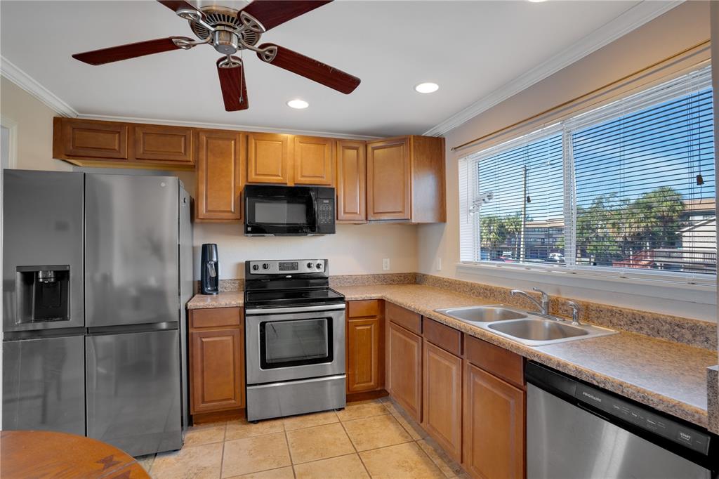 A kitchen features wood cabinets, stainless steel appliances, tile flooring, and a window with blinds — 6315 NEWTOWN CIRCLE UNIT 15B3, TAMPA, FL