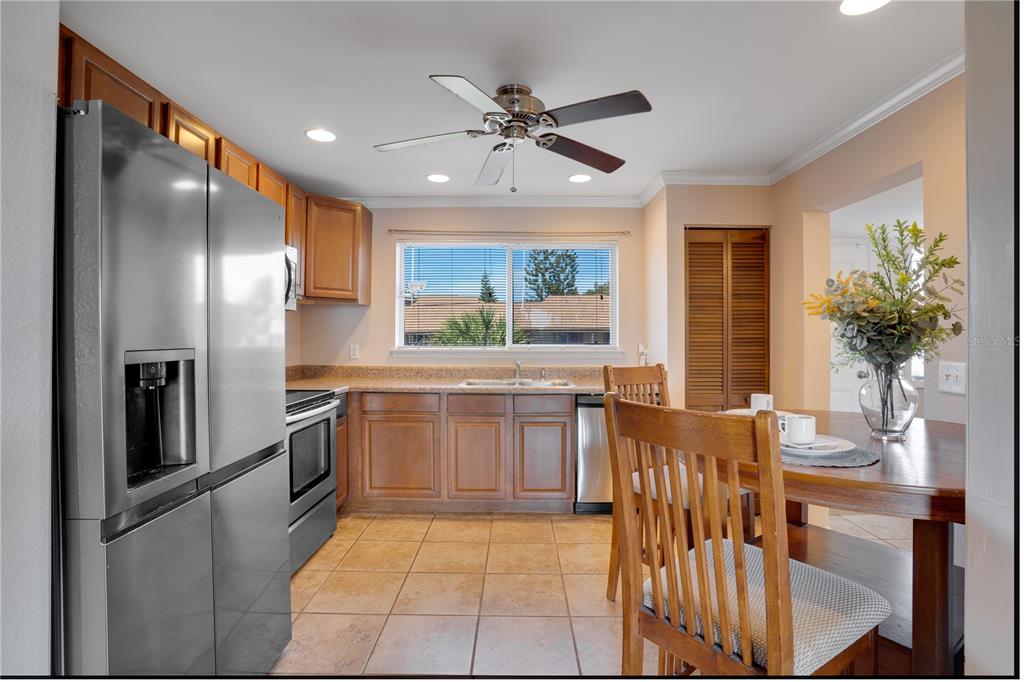 A kitchen with wood cabinets, stainless steel appliances, tile flooring, and a dining area — 6315 NEWTOWN CIRCLE UNIT 15B3, TAMPA, FL