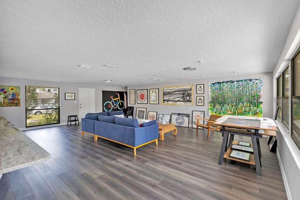 A living room with gray walls, wood-look flooring, a blue sofa, and numerous framed artworks — 3021 PLAZA TERRACE DRIVE, ORLANDO, FL