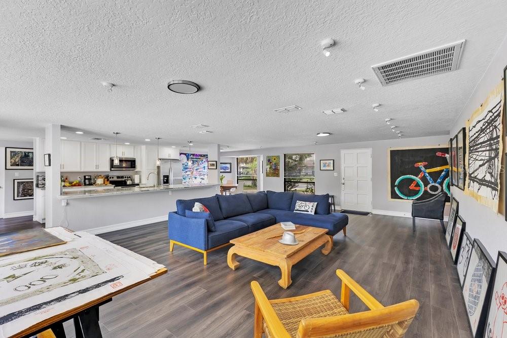 A living room with a blue sectional sofa, wood coffee table, and open-concept kitchen — 3021 PLAZA TERRACE DRIVE, ORLANDO, FL