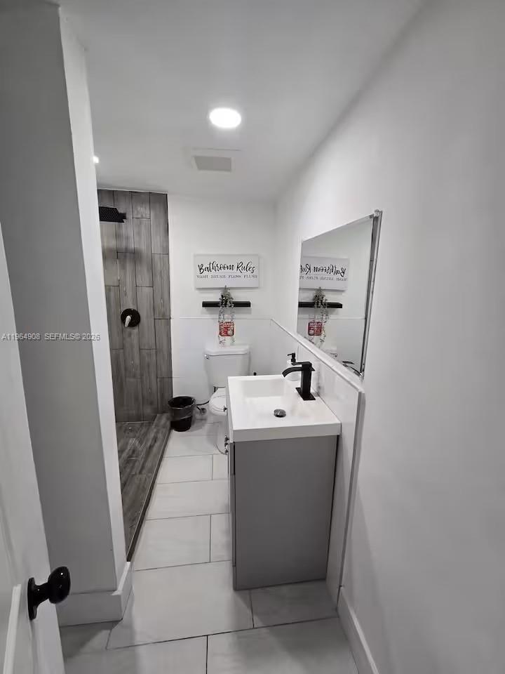 A modern bathroom features a gray vanity, a walk-in shower with wood-look tile, and white walls — 845 NW 3rd St # C, Miami FL 33128, MIAMI, FL