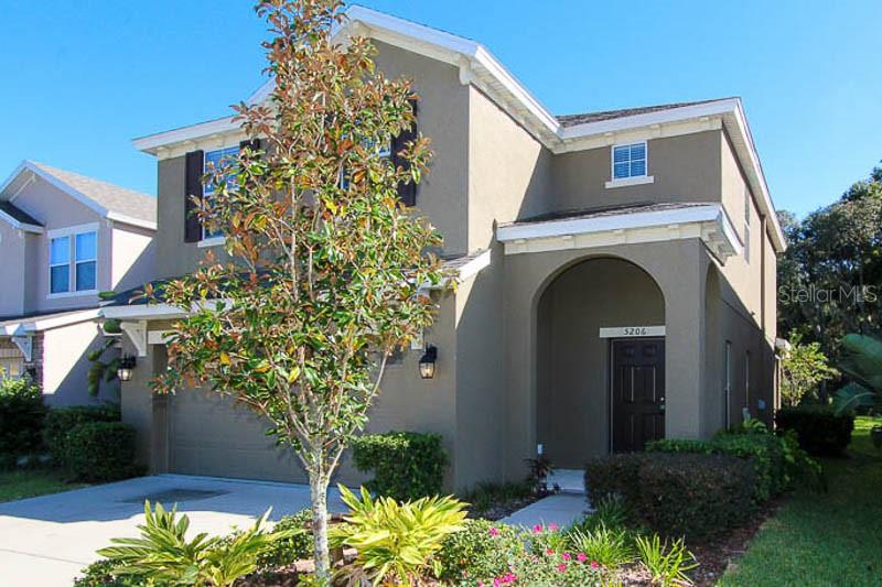 A two-story house with a tan stucco exterior, a garage, and a covered entryway — 5206 BANNISTER PARK LANE, LITHIA, FL