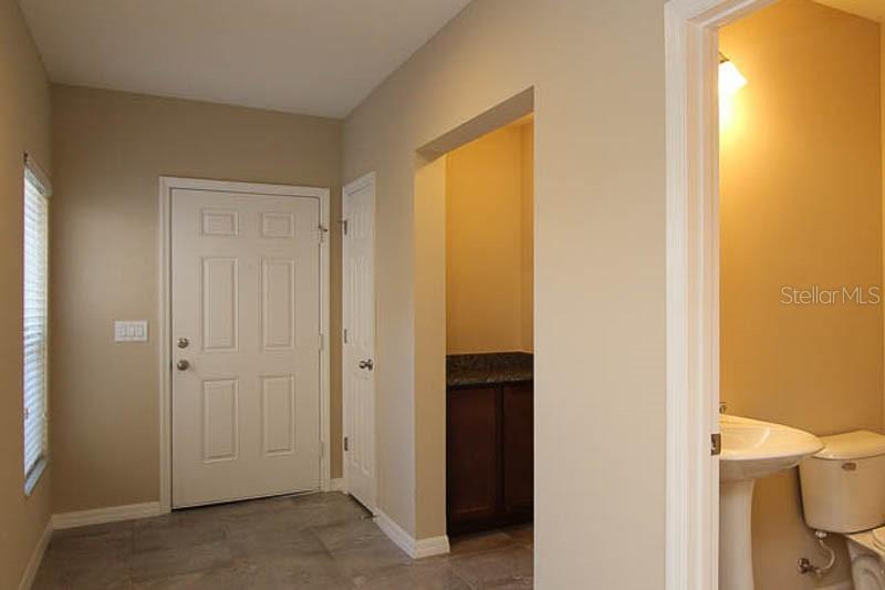 A tiled entryway features a white front door, a closet, and a half bathroom — 5206 BANNISTER PARK LANE, LITHIA, FL