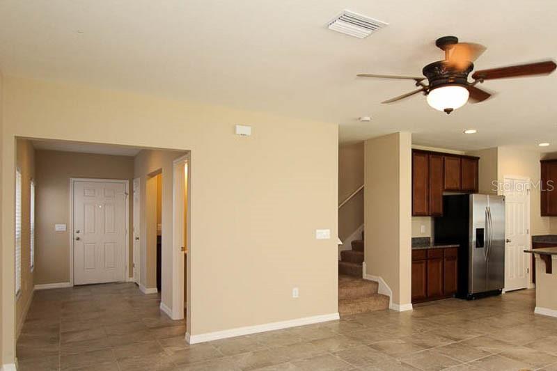 An open-concept living area features tile flooring, a ceiling fan, and an adjacent kitchen — 5206 BANNISTER PARK LANE, LITHIA, FL