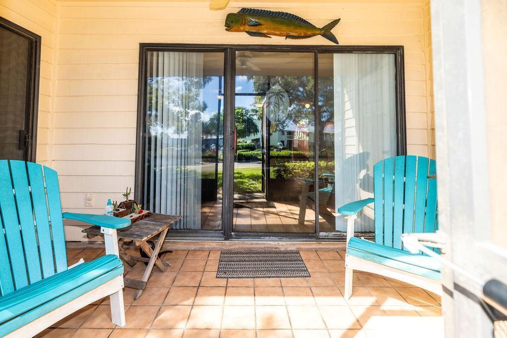 A patio with two blue chairs, a small wooden table, and a fish wall decoration — SEBASTIAN, FL