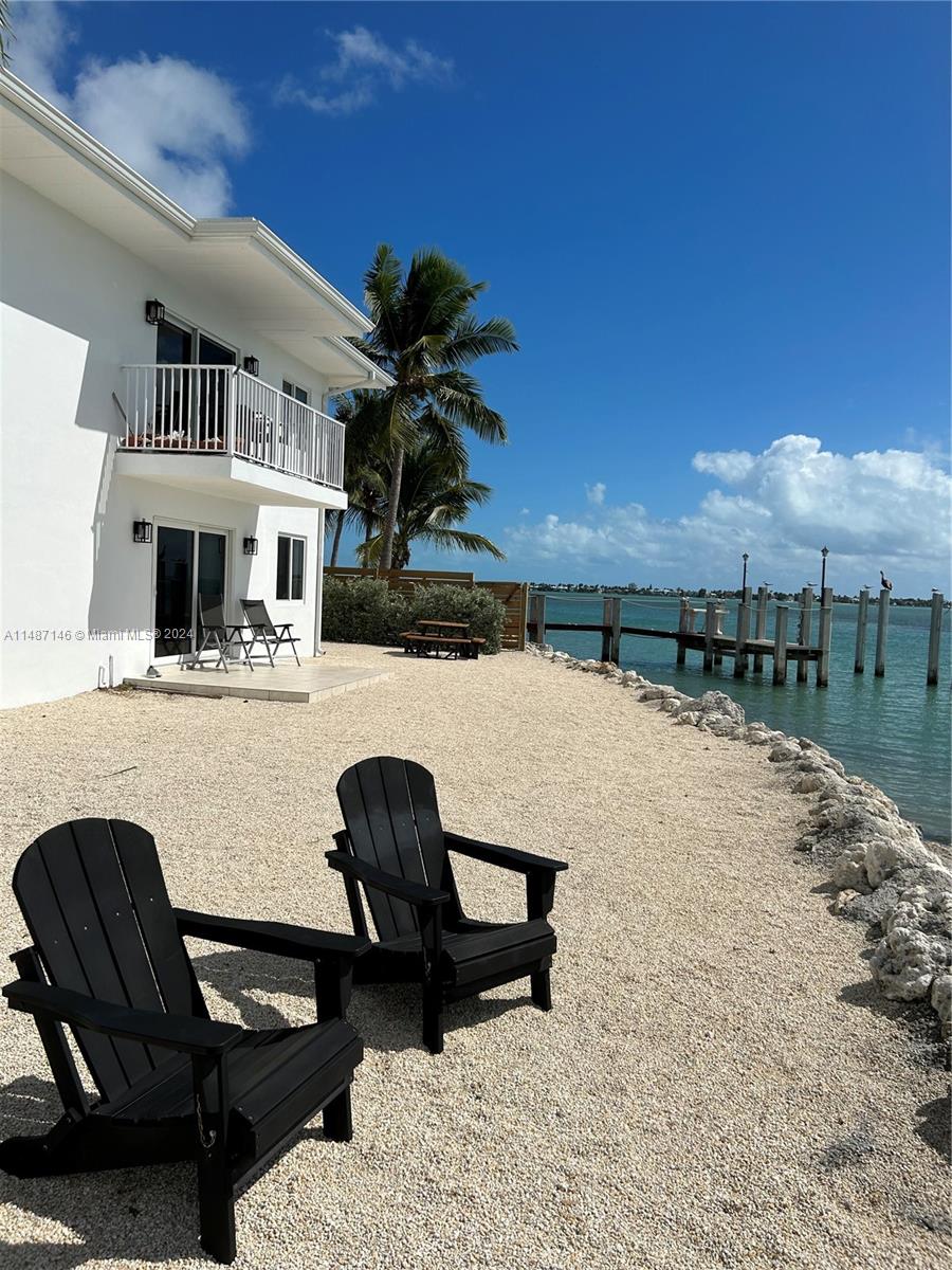 A white house with a balcony sits on a gravel shore overlooking the water — 1215 97th Street Ocean # 11, Marathon FL 33050, MARATHON, FL