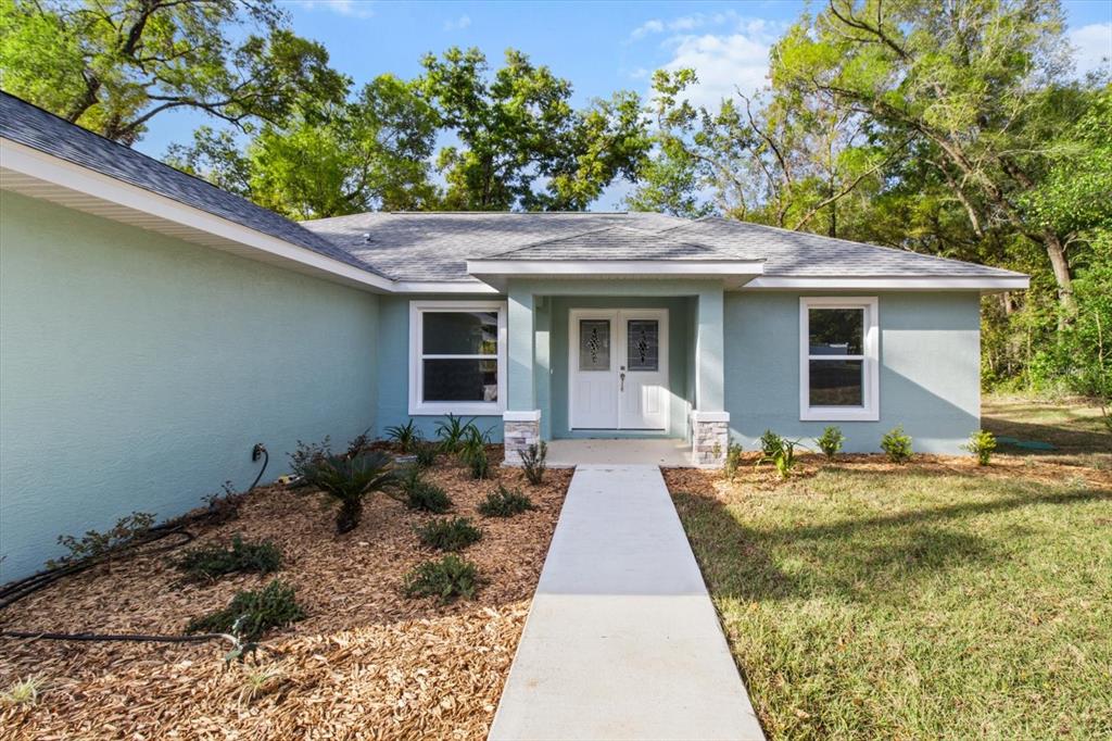 A light green single-story house with a white front door and a concrete walkway — 2396 W FAIRWAY LOOP, CITRUS SPRINGS, FL
