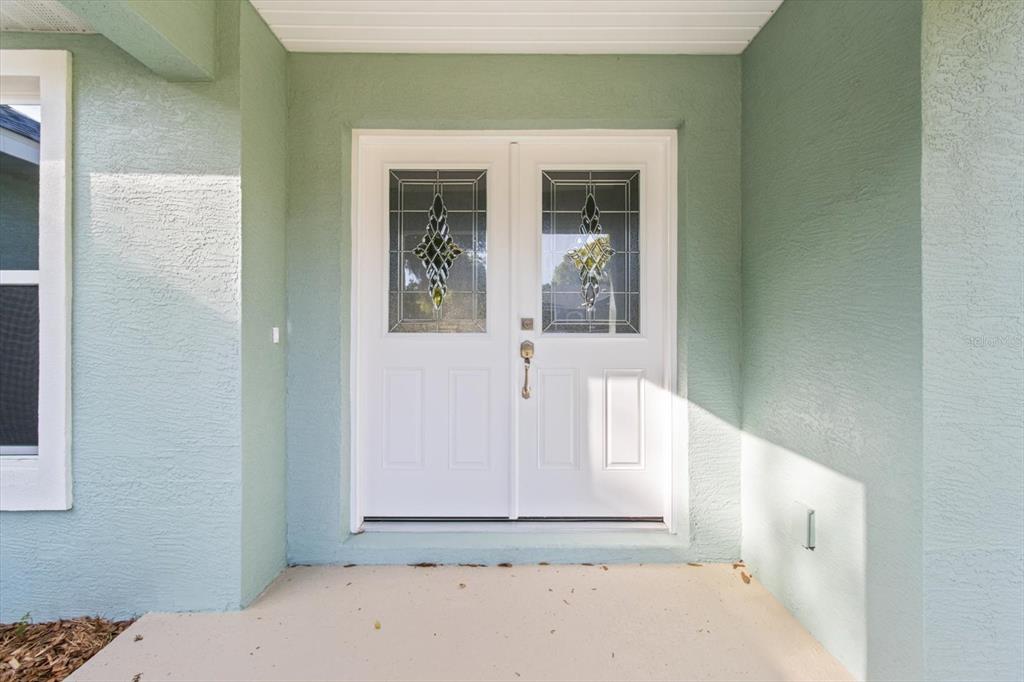 A white double front door with decorative glass inserts is set in a light green wall — 2396 W FAIRWAY LOOP, CITRUS SPRINGS, FL