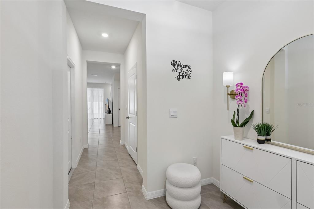 A bright entryway features a white console table, a round mirror, and a tiled hallway — 9223 ROCK HARBOUR WAY, TAMPA, FL
