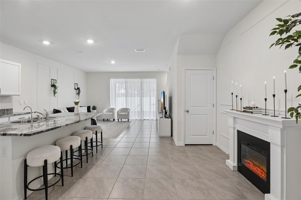 A kitchen with a marble island and bar stools opens into a living area with a fireplace — 9223 ROCK HARBOUR WAY, TAMPA, FL