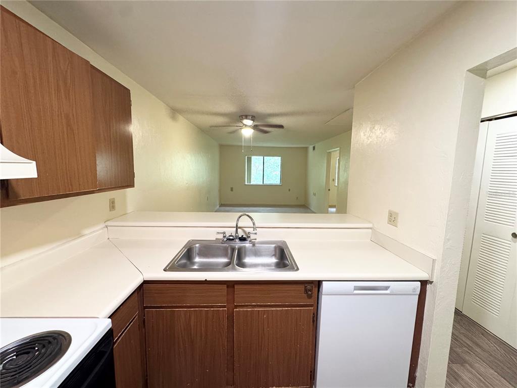 A kitchen sink and countertop overlook a living area with a ceiling fan — 83 SE 16TH AVENUE UNIT E303, GAINESVILLE, FL