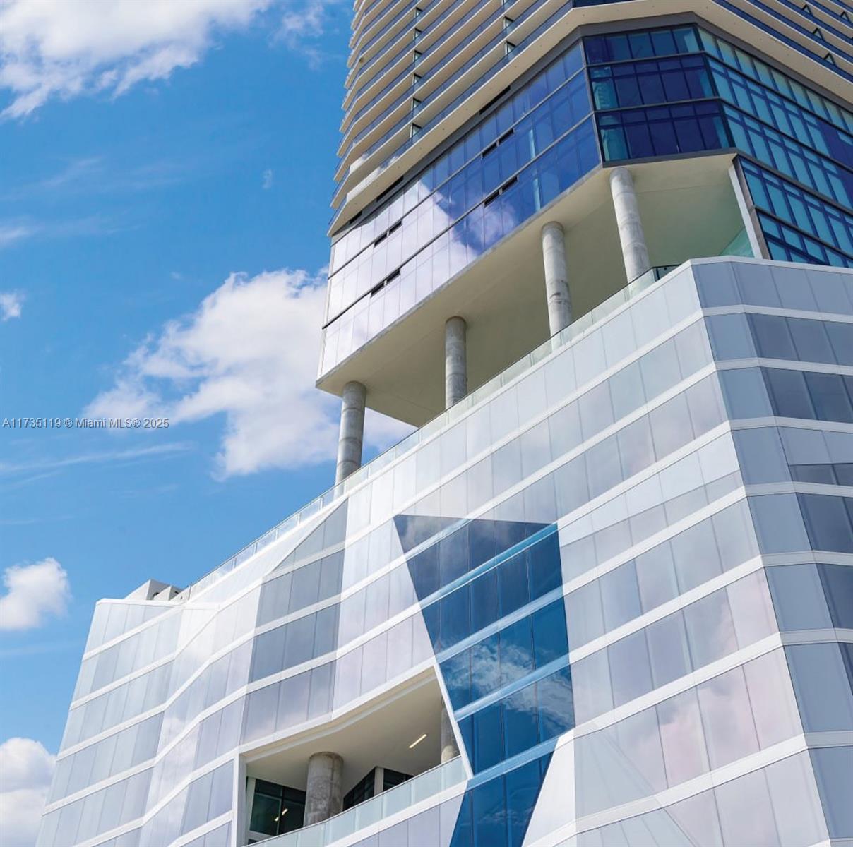 This low-angle exterior view shows the glass facade and structural columns of a modern skyscraper — 398 NE 5th St # 1510, Miami FL 33132, MIAMI, FL