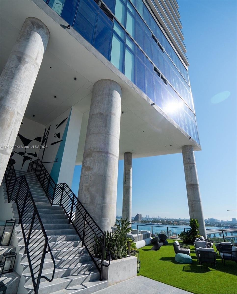 An outdoor staircase leads to a modern building terrace with concrete columns and lounge seating — 398 NE 5th St # 1510, Miami FL 33132, MIAMI, FL