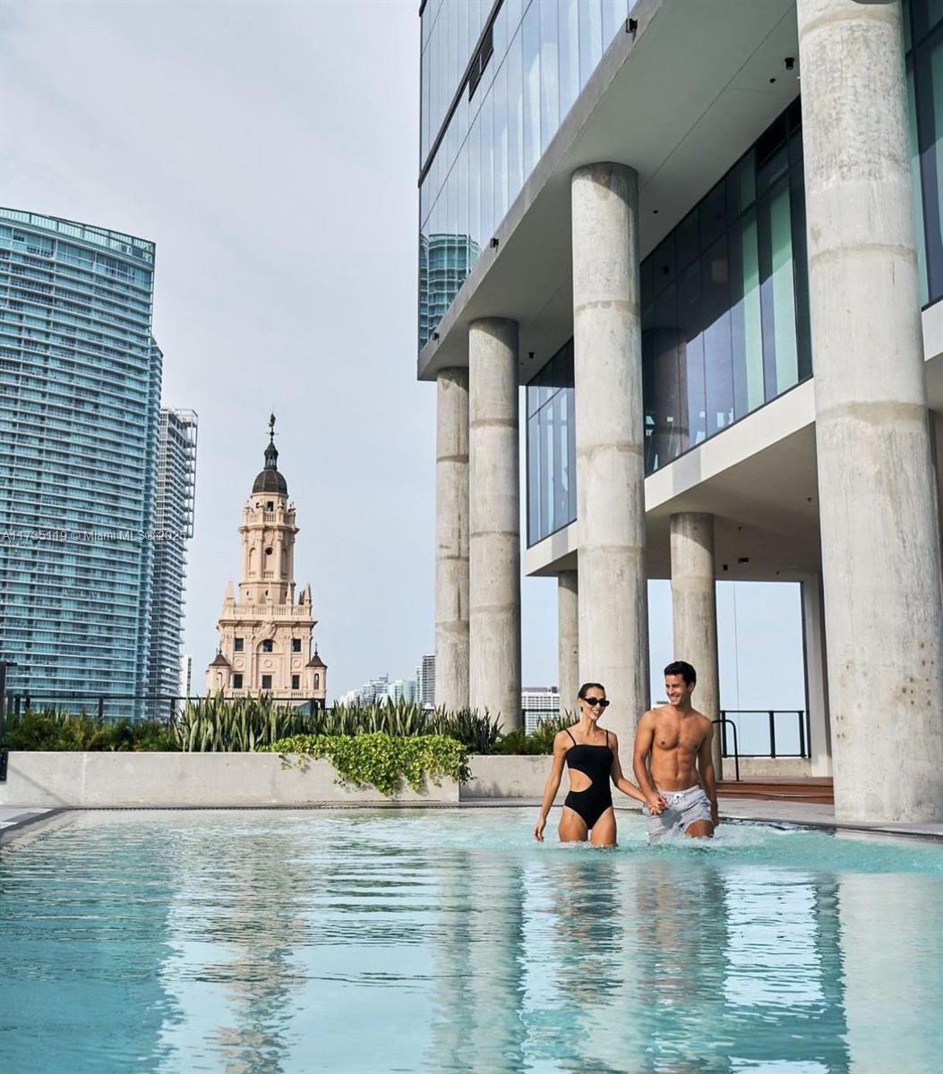 A couple walks through an outdoor swimming pool with a view of city skyscrapers — 398 NE 5th St # 1510, Miami FL 33132, MIAMI, FL