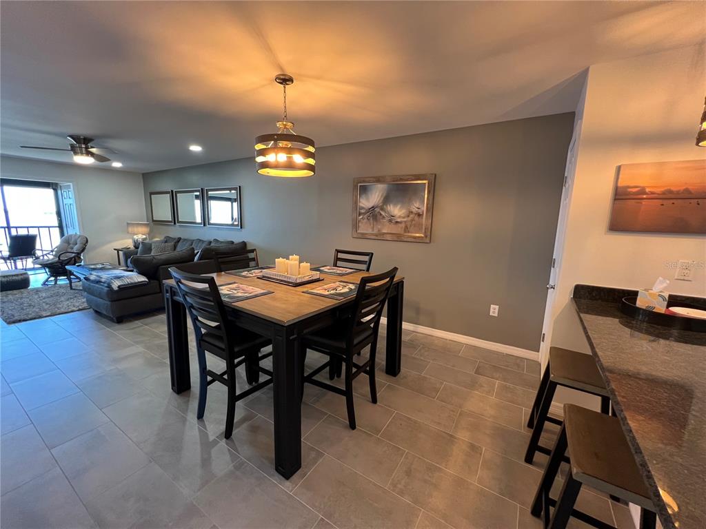 A dining area with a dark wood table and chairs sits adjacent to a living room — 14459 RIVER BEACH DRIVE UNIT 226, PORT CHARLOTTE, FL