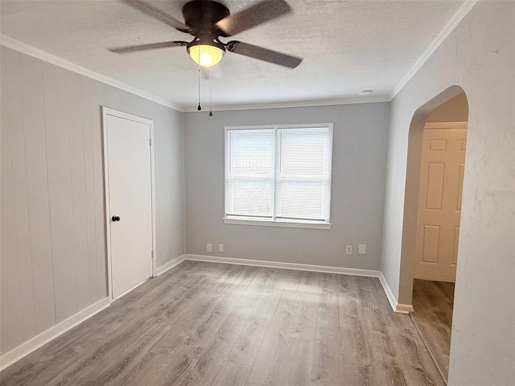 A bedroom features light gray walls, wood-look flooring, a ceiling fan, and an arched doorway — 776 27TH AVENUE N, ST PETERSBURG, FL