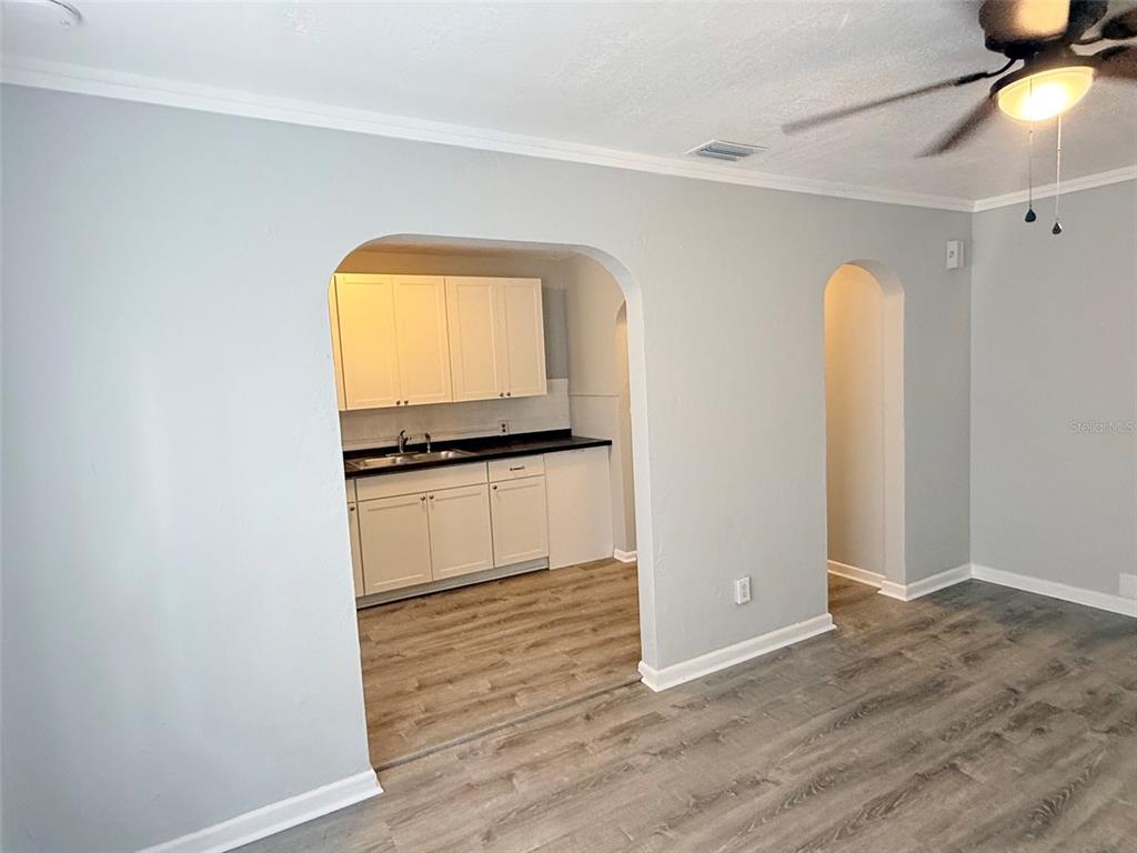 A kitchen with white cabinets and dark countertops is visible through an arched doorway — 776 27TH AVENUE N, ST PETERSBURG, FL