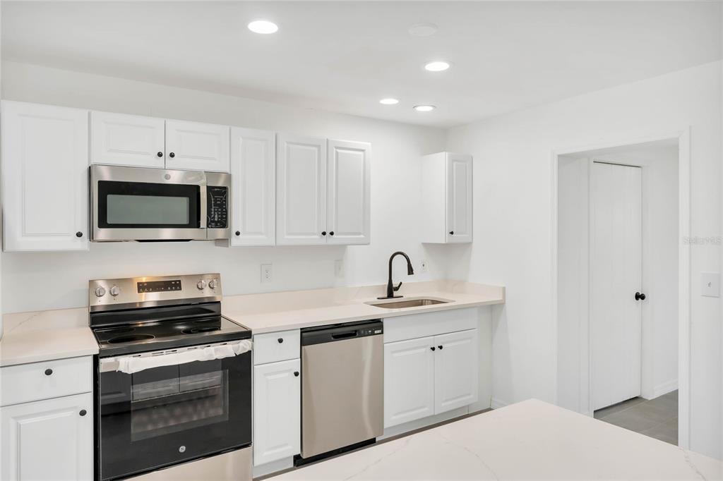 A kitchen with white cabinets, stainless steel appliances, and light-colored countertops — 448 RIDGE DRIVE, SANFORD, FL