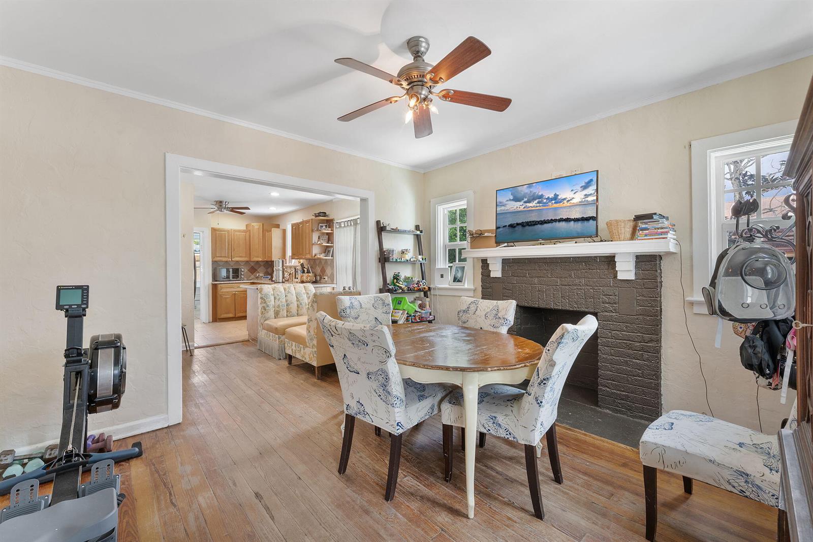 A dining room features a round table, patterned chairs, a brick fireplace, and hardwood floors — 506 Malverne Road, West Palm Beach FL 33405, WEST PALM BEACH, FL
