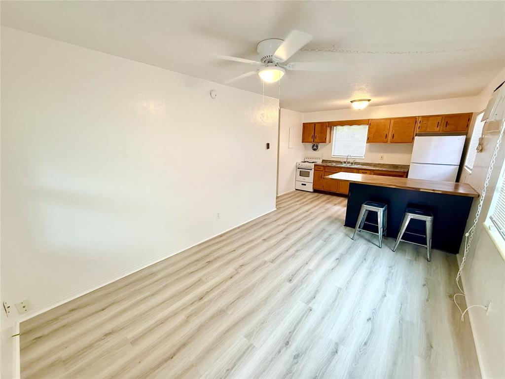 An open-concept kitchen and dining area featuring light wood-look flooring and a dark blue island — 1135 HIGHLAND STREET N UNIT 3, ST PETERSBURG, FL