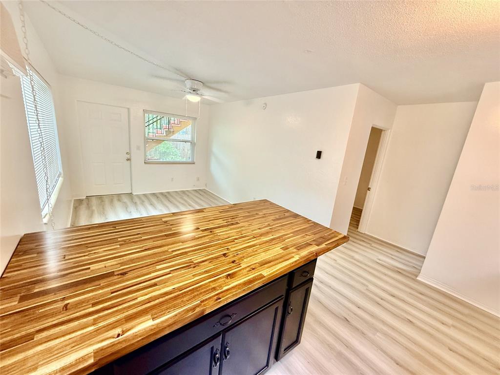 A kitchen island with a wood countertop sits in a room with light wood flooring — 1135 HIGHLAND STREET N UNIT 3, ST PETERSBURG, FL