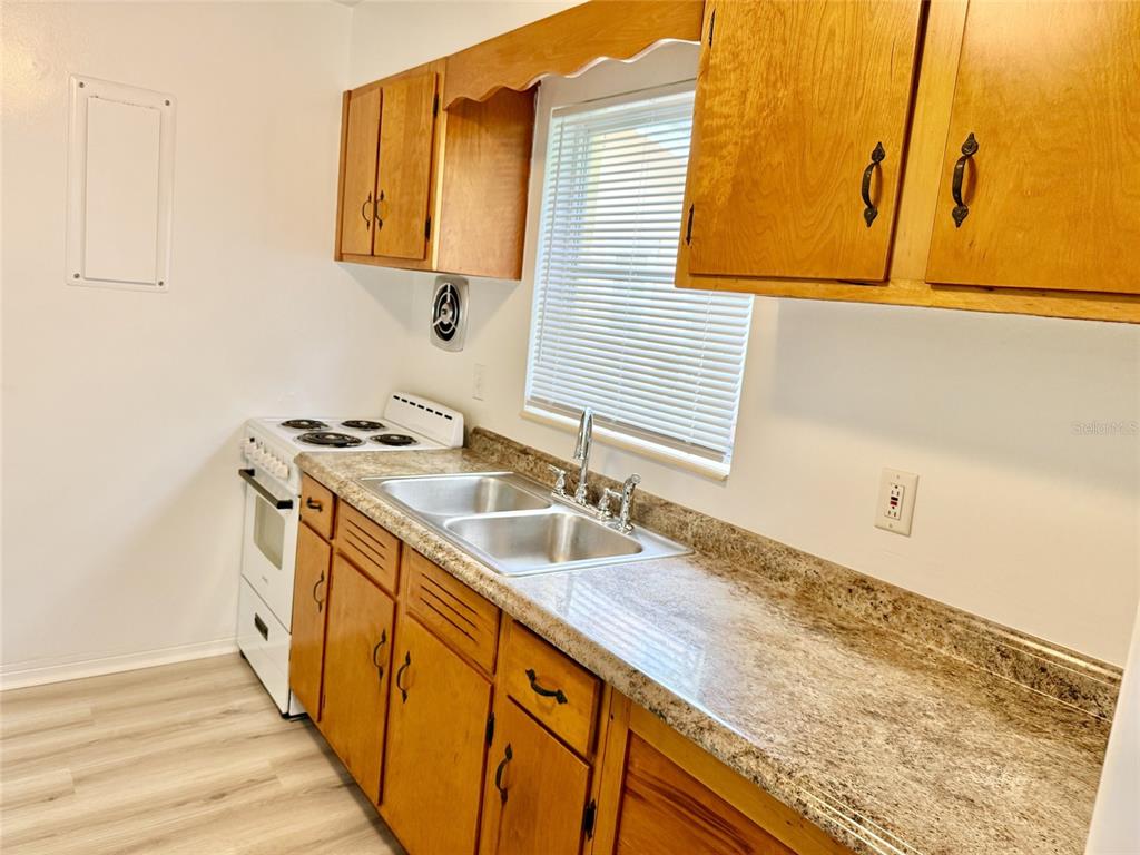 A kitchen features wood cabinets, a laminate countertop, a double sink, and a white stove — 1135 HIGHLAND STREET N UNIT 3, ST PETERSBURG, FL