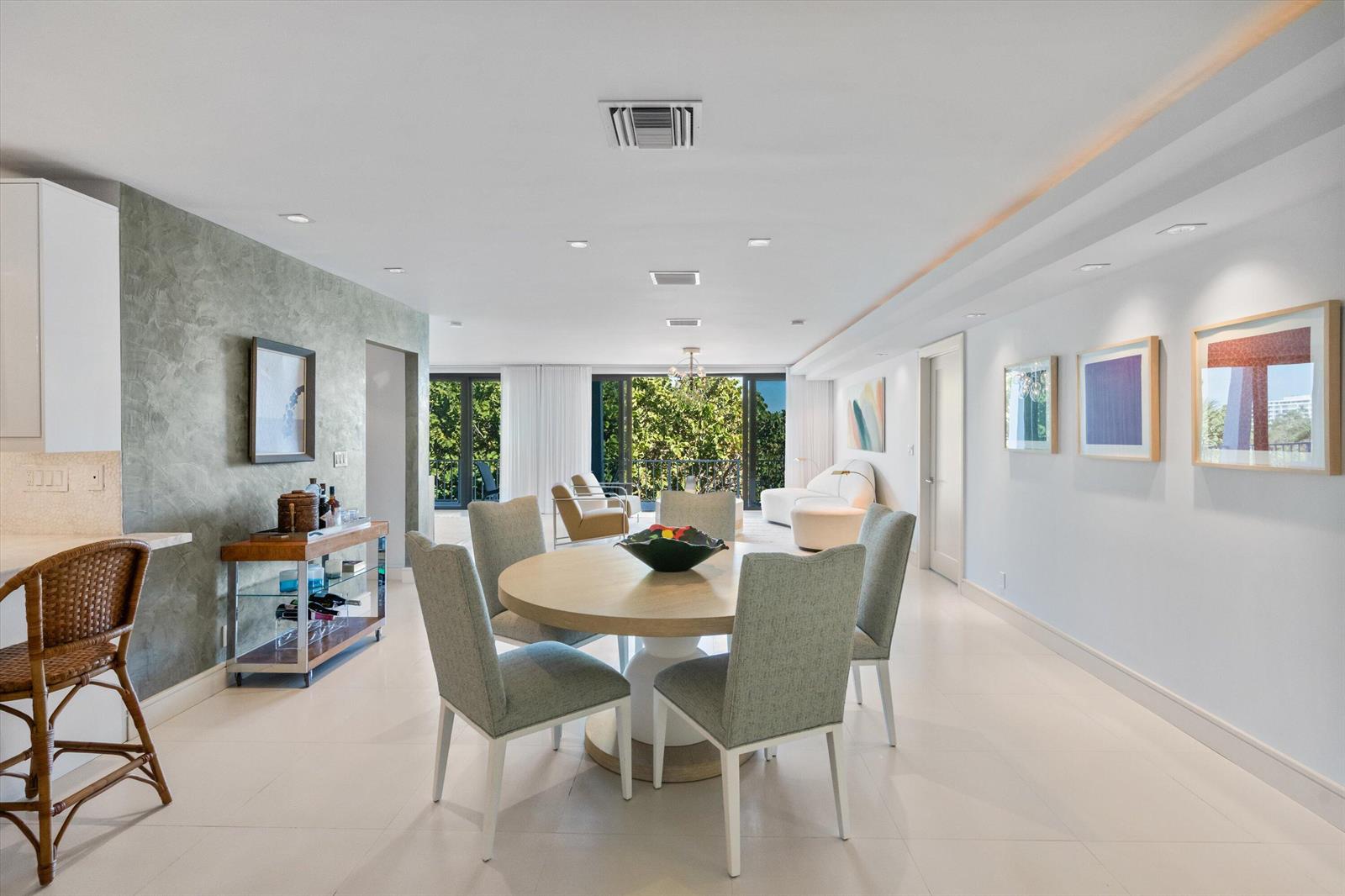 A dining area with a round table and chairs sits before a bright living space — 2275 S Ocean Boulevard, Palm Beach FL 33480, PALM BEACH, FL