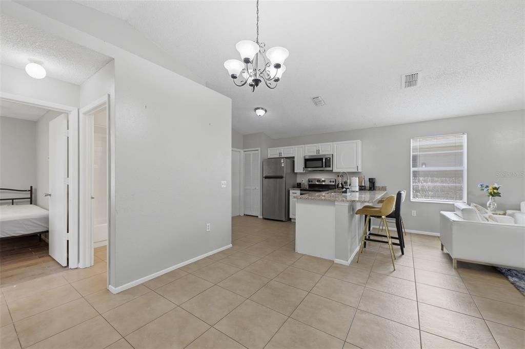 A kitchen with white cabinets and a granite island opens into a living area — 5230 FLORIDA HOLLY DRIVE, ORLANDO, FL