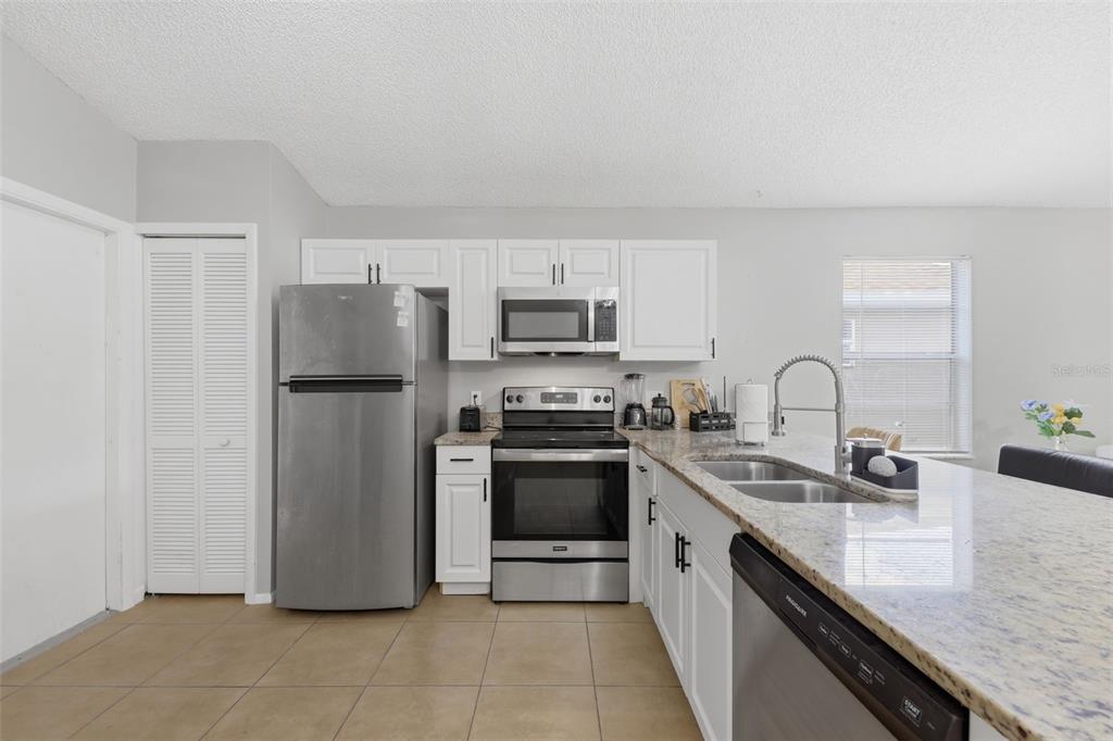 A kitchen features stainless steel appliances, white cabinets, and granite countertops — 5230 FLORIDA HOLLY DRIVE, ORLANDO, FL