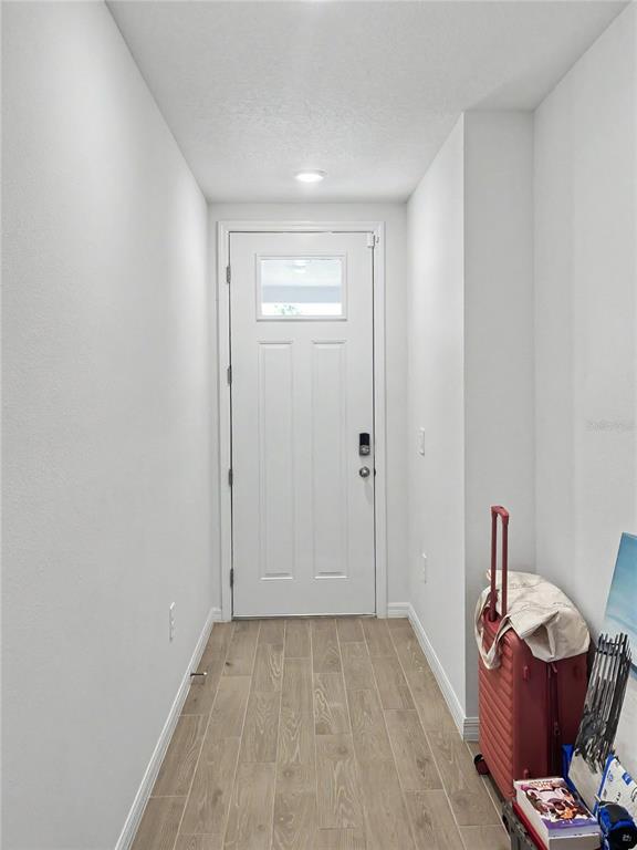 A narrow entryway features white walls, wood-look tile flooring, and a white front door — 137 WHITELAND BEND, NOKOMIS, FL
